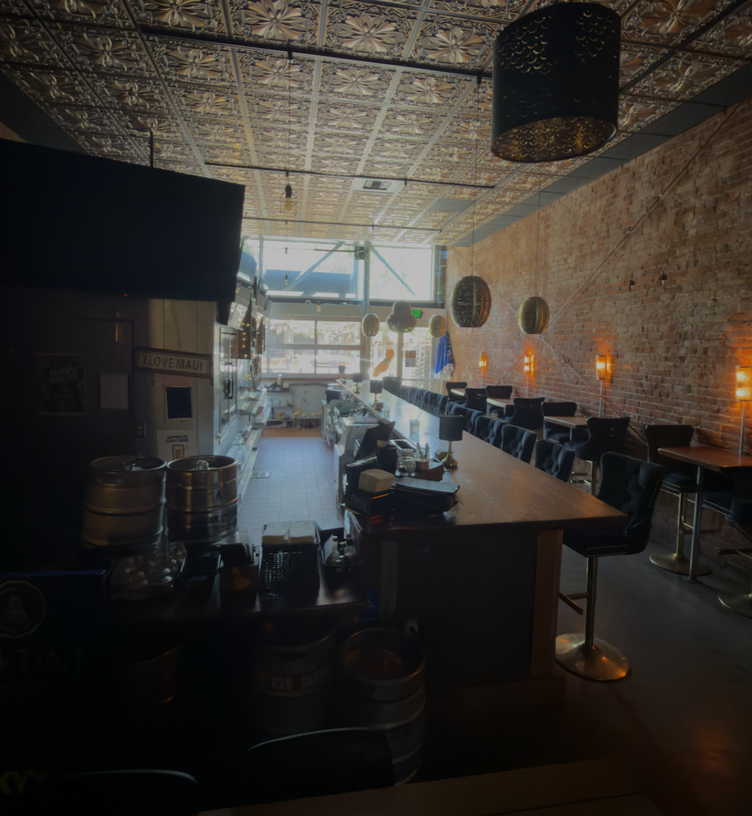 Inside Belly: long bar, exposed brick wall with warm sconces, ornate metallic ceiling and plush seating